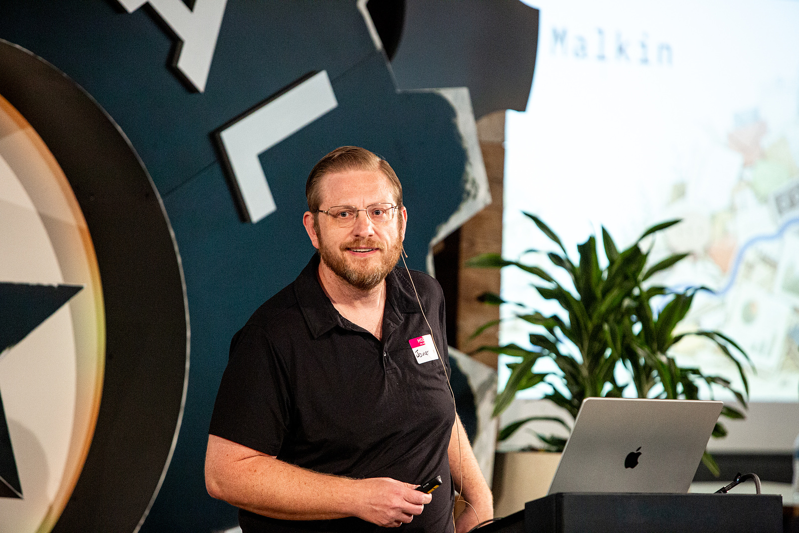 Jonathan Malkin presenting on stage in Austin, beside a laptop on a lectern.